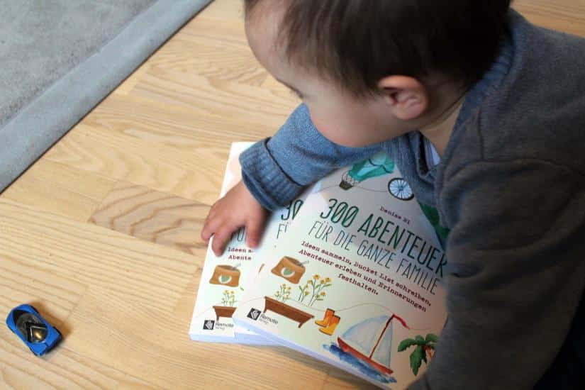 Kleinkind greift nach Bucket List Buch für Familien