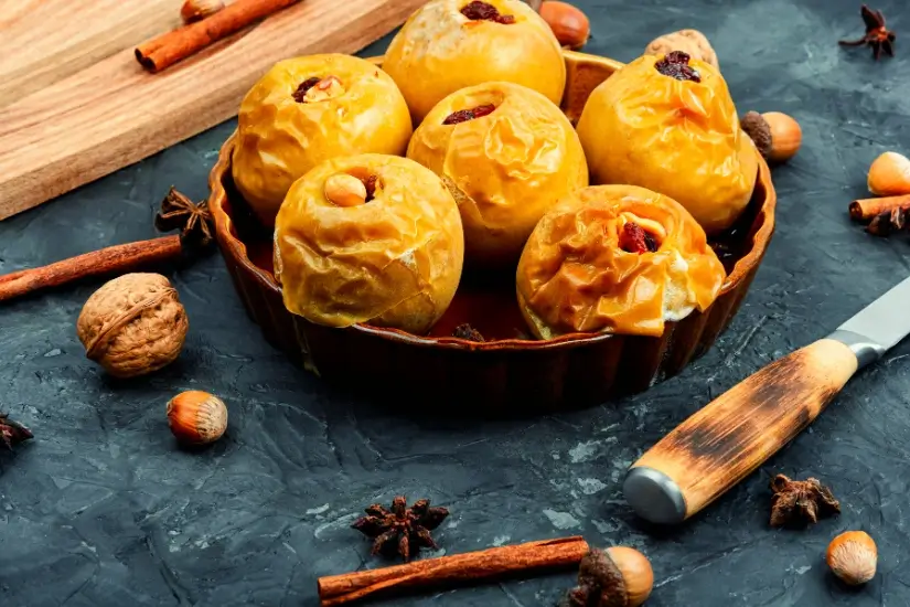 Gebackene Äpfel mit Nüssen und Zimt in einer Backform auf dunklem Untergrund