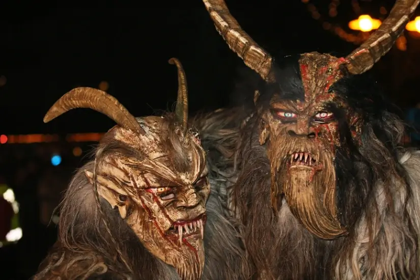 Zwei Personen in furchterregenden Krampus-Kostümen mit Hörnern und roten Augen bei Nacht
