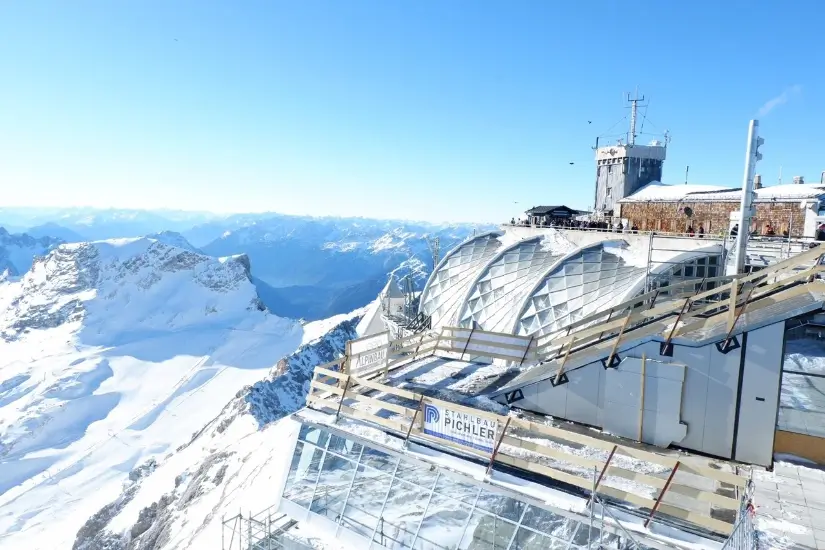 Aussicht von der Zugspitze mit Schnee, Panoramaplattform und alpiner Berglandschaft unter blauem Himmel
