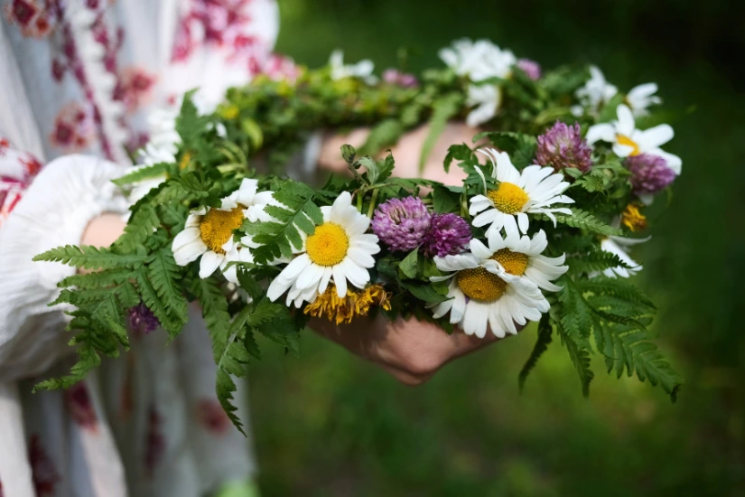 Zwei Hände halten einen Kranz aus Wiesenblumen