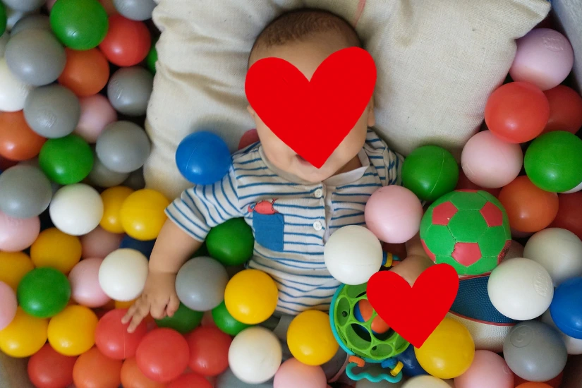 Ein Baby liegt in einem bunten Bällebad